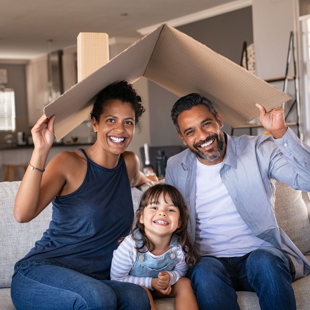 Happy family holding a piece of cardboard to simulate a roof over their head
